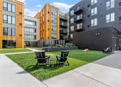 Thumbnail 102 of 103 - Two chairs are on a lawn in front of a building.