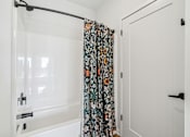 Thumbnail 72 of 99 - A white bathroom with a floral shower curtain.