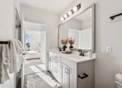 Thumbnail 77 of 99 - A bathroom with a white vanity and a mirror with lights above it.
