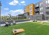 Thumbnail 98 of 103 - A modern apartment complex with a green lawn and outdoor furniture.