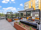 Thumbnail 77 of 103 - A modern outdoor seating area with a black metal fence and orange planters.