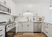 Thumbnail 2 of 103 - A modern kitchen with white cabinets and stainless steel appliances.