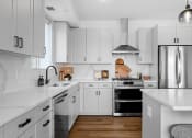 Thumbnail 17 of 103 - a white kitchen with stainless steel appliances and white counters