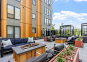Thumbnail 81 of 103 - A patio area with a black table and chairs, a couch, and a fire pit.