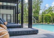Thumbnail 87 of 103 - A poolside area with lounge chairs and a building in the background.