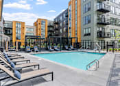 Thumbnail 93 of 103 - A swimming pool surrounded by lounge chairs and apartment buildings.