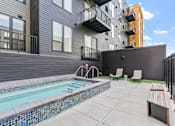 Thumbnail 84 of 103 - A small pool with a bench and a chair in front of a building.