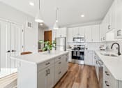 Thumbnail 59 of 99 - A modern kitchen with white cabinets and a wooden floor.