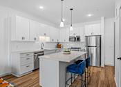 Thumbnail 110 of 113 - A kitchen with white cabinets and a white island with blue chairs.