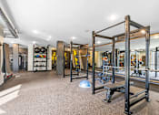 Thumbnail 36 of 103 - A gym with a variety of equipment including a squat rack and a bench press.