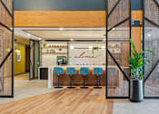 Thumbnail 36 of 99 - A modern interior with a wooden bar and blue bar stools.