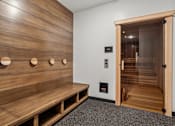 Thumbnail 32 of 103 - A wooden bench with circular cutouts on the back is in a room with a wooden wall and a door.
