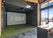 Thumbnail 40 of 99 - A room with a green carpet and a screen displaying "All Seasons GOLF".