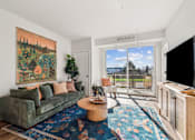 Thumbnail 67 of 99 - A living room with a green couch and a large painting on the wall.