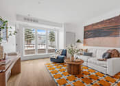 Thumbnail 1 of 113 - A living room with a white couch, a coffee table, and a large painting on the wall.