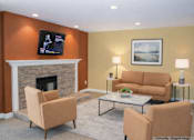 Thumbnail 12 of 12 - A living room with a fireplace, two chairs, a couch, and a painting on the wall.