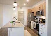 Thumbnail 26 of 75 - A kitchen with a sink, refrigerator, and oven at Parc on 5th Apartments & Townhomes