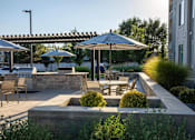 Thumbnail 70 of 75 - A patio with a table and chairs under umbrellas at Parc on 5th Apartments & Townhomes