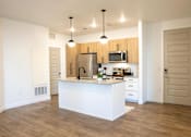 Thumbnail 27 of 75 - A kitchen with wooden cabinets and a white island at Parc on 5th Apartments & Townhomes