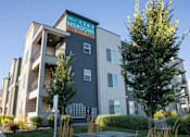 Thumbnail 74 of 75 - A modern apartment building with a sign that reads "1, 2 & 3 Bedroom" and a phone number.