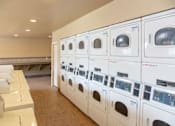Thumbnail 10 of 26 - Laundry Center with Machines Next to Folding Counter at Aspen Park Apartments, Sacramento