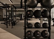 Thumbnail 62 of 85 - A gym with a rack of black exercise balls.