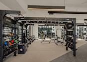 Thumbnail 24 of 85 - A gym with a variety of equipment including a squat rack, weight bench, and a rowing machine.