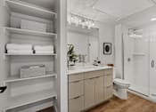 Thumbnail 9 of 85 - A bathroom with a white toilet, sink, and a white cabinet with a plant on top.