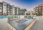 Thumbnail 33 of 45 - A poolside area with a hot tub and seating area in front of apartment buildings.