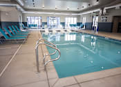 Thumbnail 11 of 34 - A large indoor swimming pool with blue water and metal handrails.