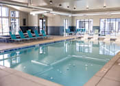 Thumbnail 12 of 34 - A large indoor swimming pool with lounge chairs.