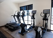 Thumbnail 19 of 34 - A gym with treadmills, elliptical machines, and a stationary bike.