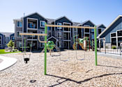 Thumbnail 22 of 34 - A playground with swings and a slide in front of apartment buildings.