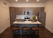 Thumbnail 3 of 34 - A kitchen with a white countertop and brown bar stools.