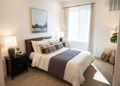 Thumbnail 7 of 34 - A bedroom with a large bed and a painting on the wall.