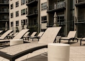 Thumbnail 72 of 85 - A row of sun loungers are in front of a building.