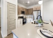 Thumbnail 19 of 54 - A kitchen with a white countertop and wooden cabinets.