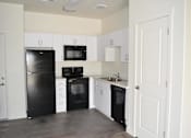 Thumbnail 8 of 16 - Modern Kitchen with Black Appliances and White Cabinets at Kimpton Square Senior Apartments