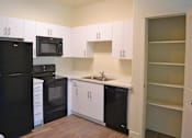 Thumbnail 2 of 16 - Modern Kitchen with Black Appliances and White Cabinets at Kimpton Square Senior Apartments