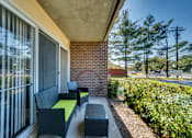 Thumbnail 11 of 14 - A patio with a bench and a table with a green cushion.