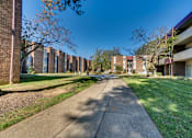 Thumbnail 6 of 14 - A long concrete walkway leads between apartment buildings.