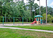 Thumbnail 16 of 18 - A playground with a green swing set and a red slide. Aviary Village Apartments, in Conway, SC 29526