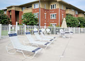Thumbnail 13 of 18 - Aviary Village Apartments, in Conway, SC 29526 A white and blue lounge chair is in front of a red brick building.