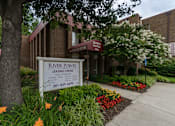 Thumbnail 5 of 14 - A leasing center named River Pointe is surrounded by greenery and flowers.