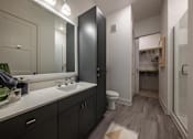 Thumbnail 27 of 30 - A large bathroom with a sink, mirror, toilet, linen closet, stand-up shower and access to a walk-in closet.