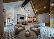 Thumbnail 9 of 30 - A clubhouse with four seating areas with chairs and tables near a lounge with sofas and a TV/