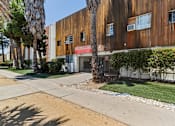 Thumbnail 3 of 10 - A building with a red awning is surrounded by trees and shrubs.