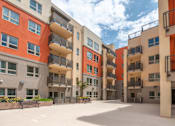 Thumbnail 4 of 17 - A large open courtyard surrounded by orange and beige buildings with balconies.