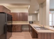 Thumbnail 15 of 17 - A modern kitchen with dark wood cabinets and a black refrigerator.