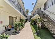 Thumbnail 9 of 10 - A long, narrow courtyard between two buildings with a metal staircase on the right.